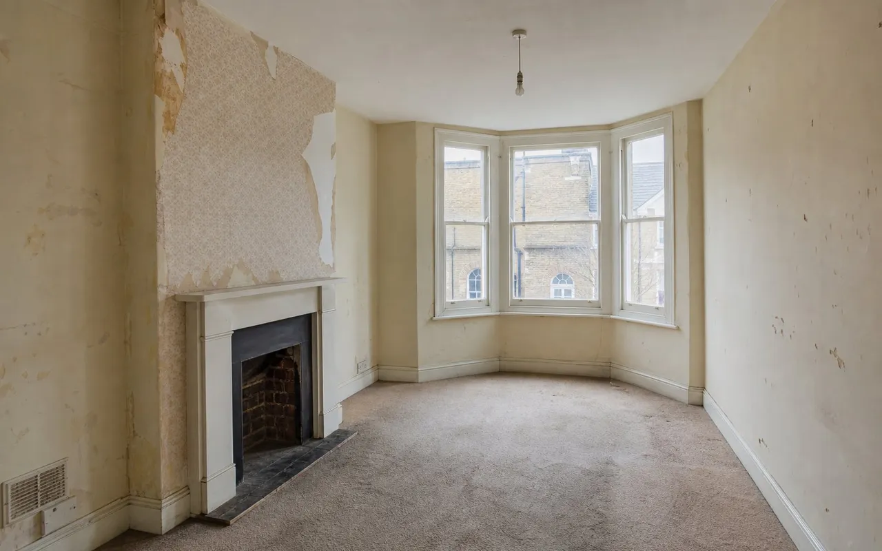 Flat before refurbishment: marked walls, worn flooring and tired finishes